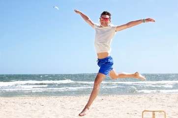 Young man leaping mid air on beach, Port Melbourne, Melbourne, Australia by .