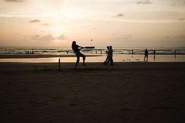 People playing cricket on mumbai beach by .