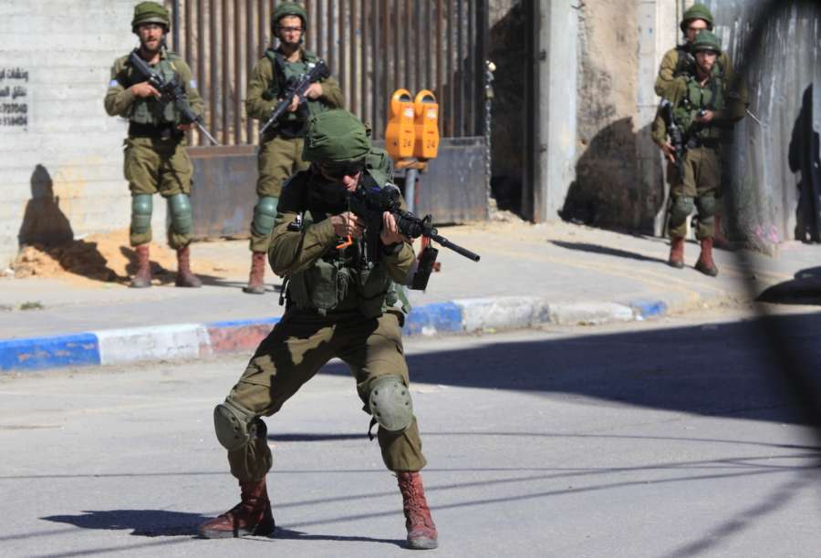 HEBRON, March 31, 2018 (Xinhua) -- Israeli soldiers take positions during a clash with Palestinian protesters in the West Bank city of Hebron, on March 31, 2018. The clash broke out after Friday that left some 15 Palestinians killed and more than 1,400 wounded by the Israeli Defense Forces gunfire in the clashes along the Israel-Gaza border. (Xinhua/Mamoun Wazwaz/IANS) by .